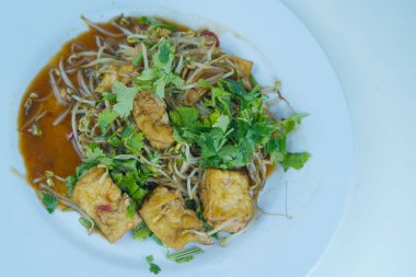 Soya fasulyesi filizi ve tofu, kişniş yapraklarıyla serpilmiş, beyaz bir tabakta servis ediliyor. Ayrı bir yemek fotoğrafı..