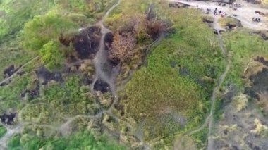 Küçük bir gölün üzerinde bir dron uçar. Dağlık arazi hatlarıyla çevrili kuru bitki örtüsüyle ve Endonezya 'nın Batı Surabaya kentindeki birkaç yüksek binanın zeminiyle. Hava görüntüleri.