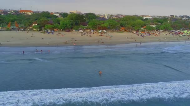 バリ島のレギャンビーチ クタの賑やかな雰囲気は ドローンを使用して空気から撮影された混雑した日の木々やホテルを眺めることができます エアリアルビデオ — ストック動画
