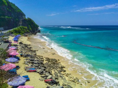 Bali 'deki Pandawa Sahili' nin havadan görünüşü, beyaz kumlu kıyıları, çarpıcı kireçtaşı kayalıkları ve parlak mavi gökyüzü ile nefes kesici. İnsansız hava aracı ile hava görüntüleri.