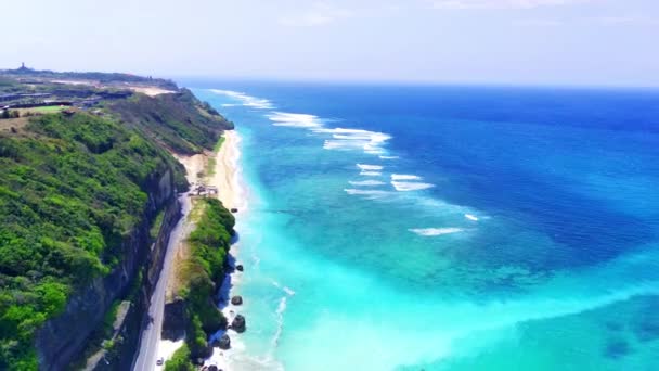 空から見ると バリのパンダワビーチは 透明な青い水 白い砂 沿岸の岩 道路の崖で育つ緑豊かな植生を誇っています ドローンで撮影した航空写真 — ストック動画