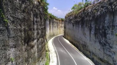 İnsansız hava aracı, Pandawa Sahili 'ndeki iki uçurum arasındaki dar bir boşluktan yavaşça geçti ve altında Hint Okyanusu' na çıkan dolambaçlı bir asfalt yol vardı. Hava sineması görüntüleri.