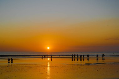 Bali 'deki Kuta Sahili' nde gün batımının tadını çıkaran insanların silueti. Sokak Fotoğrafçılığı