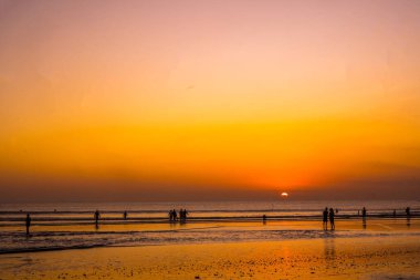 Bali 'deki Kuta Sahili' nde gün batımının tadını çıkaran insanların silueti. Sokak Fotoğrafçılığı