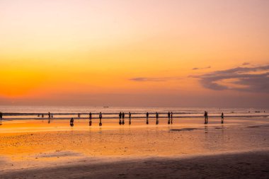 Bali 'deki Kuta Sahili' nde gün batımının tadını çıkaran insanların silueti. Sokak Fotoğrafçılığı