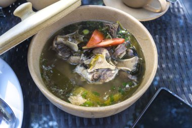 Geleneksel Endonezya Oxtail Çorbası açık kapaklı seramik bir kasede servis edilir. Taze öküz kuyruğu eti, genellikle aromatik baharat ve otlarla tatlandırılmış lezzetli bir çorbayla servis edilir.