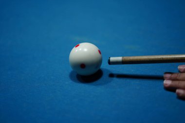 Bilardo sopasını tutan el bilardo masasındaki bilardo topuna kesin bir vuruş yapmaya hazır. Spor ve oyun fotoğrafçılığı.