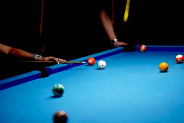 Bilardo sopasını tutan el bilardo masasındaki bilardo topuna kesin bir vuruş yapmaya hazır. Spor ve oyun fotoğrafçılığı.