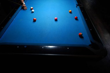 Bilardo sopasını tutan el bilardo masasındaki bilardo topuna kesin bir vuruş yapmaya hazır. Spor ve oyun fotoğrafçılığı.