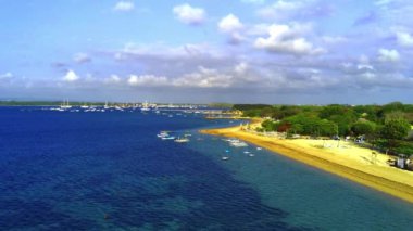 Sanur, Bali 'deki Cemara Sahili' nin güzelliği, havadan çekildi. Kremsi kum, masmavi deniz, yemyeşil ağaçlar ve sahile demir atmış birkaç tekne. Hava görüntüleri.