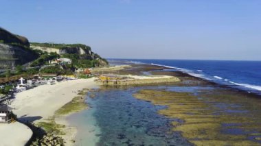 Melasti Sahili, Bali, Endonezya. Bir insansız hava aracıyla havadan çekilen, engin okyanus manzarası ve kıyı şeridi boyunca gerçekleşen etkinliklerle kumlu plajın genişliğini gözler önüne seren. Hava Görüntüsü.