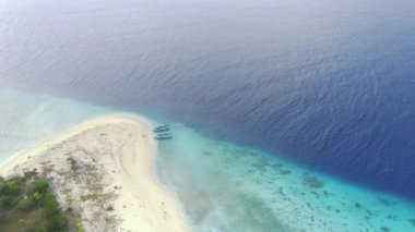 Pulau Tabuhan, Banyuwangi, Endonezya 'nın berrak sularının üzerinde süzül ve okyanustaki geleneksel balıkçı teknelerine tanık ol..