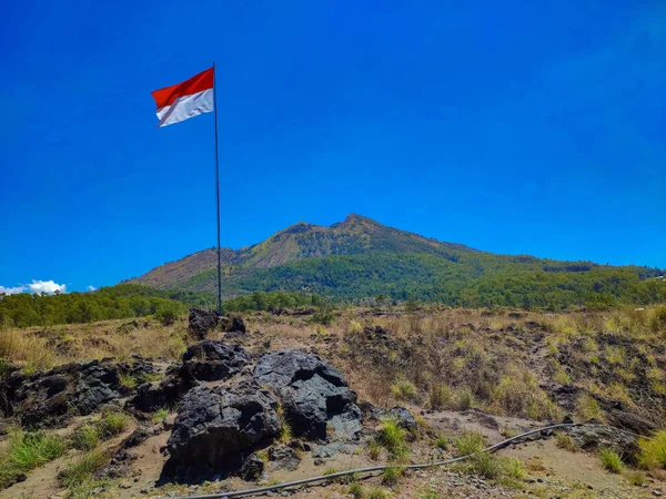 Indonesia flag waving with the background of Mount Batur, Kintamani, Bali, Indonesia during the daylight in dry season.