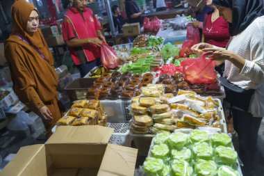 24 Kasım 2023. Surabaya, Endonezya. Pasar Kue Subuh ya da pazar yerinde şafak vakti abur cubur satılıyor. Kalabalık bir pazar yerinde insanlar renkli tezgahların etrafında toplanmış çeşitli abur cuburlarla dolup taşıyor. Sokak Editörü Fotoğrafçılık.