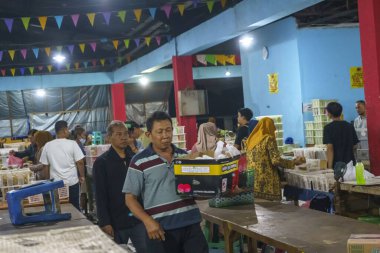 24 Kasım 2023. Surabaya, Endonezya. Pasar Kue Subuh ya da pazar yerinde şafak vakti abur cubur satılıyor. Kalabalık bir pazar yerinde insanlar renkli tezgahların etrafında toplanmış çeşitli abur cuburlarla dolup taşıyor. Sokak Editörü Fotoğrafçılık.