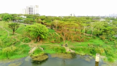 Surabaya, Endonezya 'daki tepelerde ağaçlarla çevrili küçük göl manzarası. Drone Görüntüsü