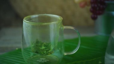Pouring boiling hot water in glass teapot with fresh bay leaves. Healthy herbal drink from Indonesia.