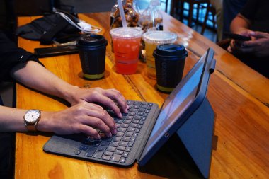Cafe 'de çalışan iPad' e el yazısı yazmak. Tahta masada biraz içecekle.