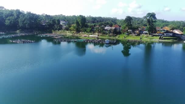ラヌパキスタンの穏やかな湖の空中観察 インドネシアの東ジャワでは カラフルな家 ドック ボートが水面にぶら下がっています 緑の木が海岸に並んでいる — ストック動画