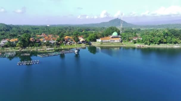 一个宁静的湖的空中景观 后面是一座白色的清真寺 有一个穹顶和高耸的尖塔 湖周围绿树成荫 印度尼西亚东爪哇Lumajang Ranu Pakis附近 — 图库视频影像
