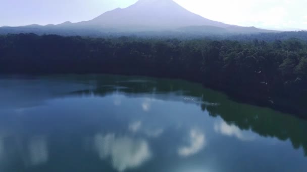 透明な湖は劇的な山脈を反映しています ラヌパキス ルマジャン 東ジャワ インドネシアの近くの湖の端を取り囲む緑豊かな森 — ストック動画