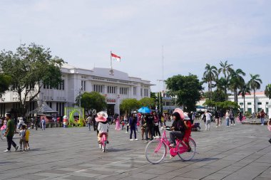 11 Nisan 2024. Jakarta, Endonezya. Hareketli sokaklar, şenlikli dekorasyonlar, geleneksel giysili aileler, bayram hediyeleri satan satıcılar, ibadet edenlerle dolu camiler, neşeli atmosfer.