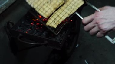 Juhi 'yi ızgara yapan bir sokak satıcısını gösteren bir video ya da Endonezya, Jakarta' da geleneksel kömür ızgarası üzerinde kurutulmuş kalamar..