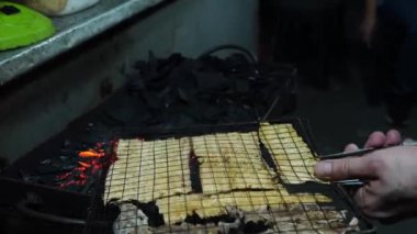 Juhi 'yi ızgara yapan bir sokak satıcısını gösteren bir video ya da Endonezya, Jakarta' da geleneksel kömür ızgarası üzerinde kurutulmuş kalamar..