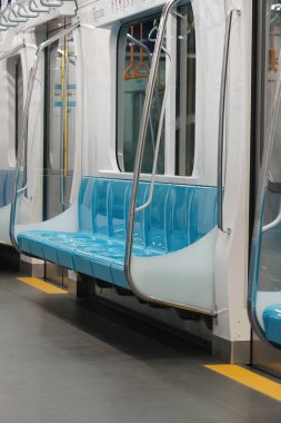 Mavi koltukları ve paslanmaz çelik parmaklıkları olan boş bir MRT Jakarta arabası. İç Fotoğrafçılık