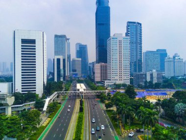 Jakarta, Endonezya 'daki Jalan Jenderal Sudirman' ın şehir manzarası. Uzun gökdelenler işlek cadde, arabalar ve insanlar aşağıda hareket ediyor..