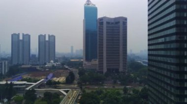 Jakarta, Endonezya 'daki Jalan Jenderal Sudirman' ın şehir manzarası. Uzun gökdelenler işlek caddede, arabalar ve insanlar aşağıda hareket ediyor. Hava görüntüleri