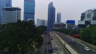 Jakarta, Endonezya 'daki Jalan Jenderal Sudirman' ın şehir manzarası. Uzun gökdelenler işlek caddede, arabalar ve insanlar aşağıda hareket ediyor. Hava görüntüleri