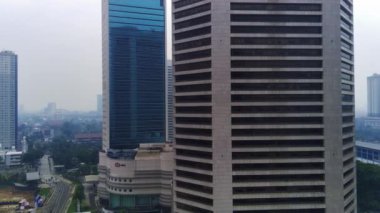 Jakarta, Endonezya 'daki Jalan Jenderal Sudirman' ın şehir manzarası. Uzun gökdelenler işlek caddede, arabalar ve insanlar aşağıda hareket ediyor. Hava görüntüleri