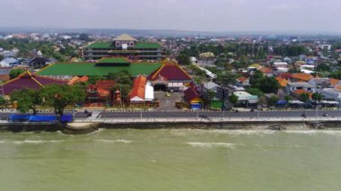 Doğu Java 'daki Tuban kıyı şeridi boyunca bir şehir. Sahilde evler ve okyanusta sallanan tekneler var..