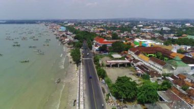 Doğu Java 'daki Tuban kıyı şeridi boyunca bir şehir. Sahilde evler ve okyanusta sallanan tekneler var..