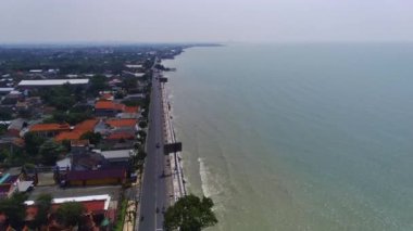 Doğu Java 'daki Tuban kıyı şeridi boyunca bir şehir. Sahilde evler ve okyanusta sallanan tekneler var..