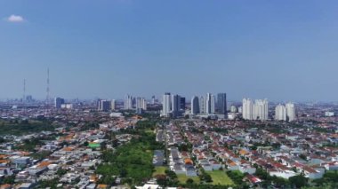 İnsansız hava aracı Surabaya şehri ve yerleşim alanının görüntülerini alıyor. İnsansız hava aracı, yüksek binalar ve ağaçlarla çevrili evleri olan bir mahallede uçuyor..