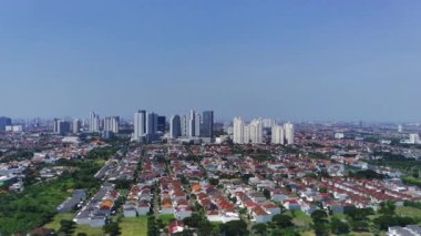 İnsansız hava aracı Surabaya şehri ve yerleşim alanının görüntülerini alıyor. İnsansız hava aracı, yüksek binalar ve ağaçlarla çevrili evleri olan bir mahallede uçuyor..