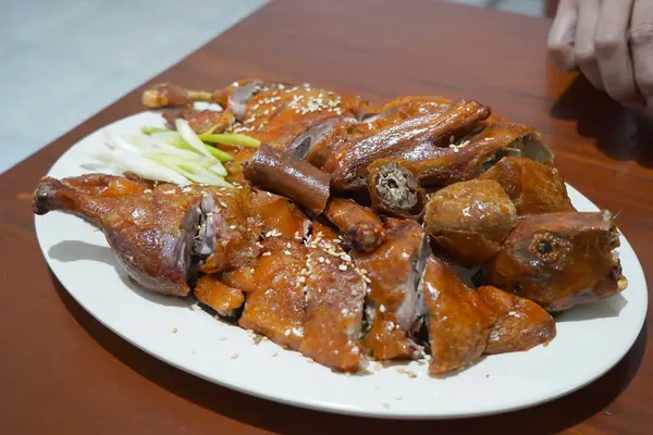 stock image a roasted duck breast on a white plate. The duck skin is brown and crispy, and it is sprinkled with sesame seeds and chopped green onions.