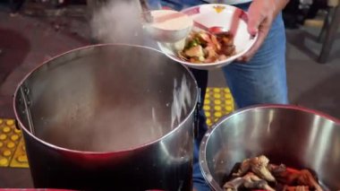 Bir insan, Endonezya kuzu çorbası ya da Sop Kambing Betawi restoranında kepçe kepçesiyle yemek yer..