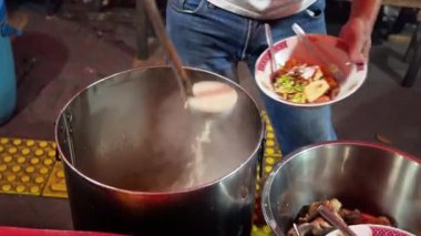 Bir insan, Endonezya kuzu çorbası ya da Sop Kambing Betawi restoranında kepçe kepçesiyle yemek yer..