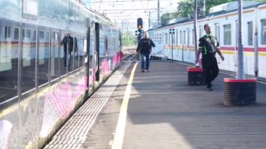 27 Haziran 2024. Jakarta, Endonezya. Birden fazla arabası olan Argobromo Anggrek yolcu treni tren istasyonunda bir platformda oturur. Yolcular trene binmek için platformda bekliyorlar..