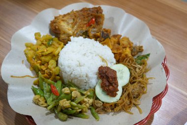 Nasi ayam campur with fragrant rice, tender chicken, and an assortment of colorful side dishes served in a restaurant. clipart