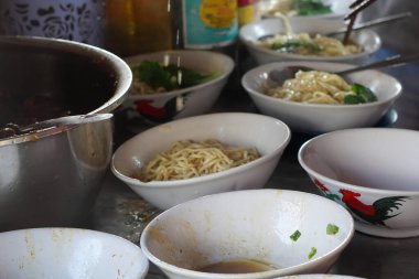 A close-up shot of Tukang Mie Ayam or a noodle vendor preparing multiple servings of chicken noodle soup. clipart