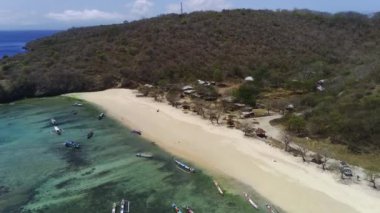 Pantai Tangsi, Lombok, Endonezya 'nın hava manzarasında el değmemiş beyaz kum, kristal berrak turkuaz su ve yemyeşil tepeler sergileniyor..