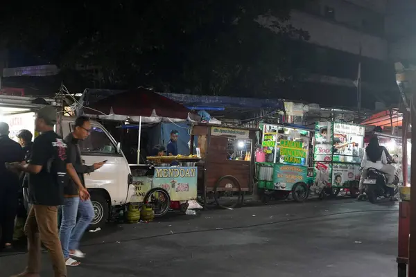 stock image August 14, 2024. Jakarta, Indonesia. A bustling night scene in a corner of the city, filled with street vendors and shoppers.