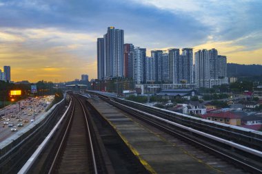 Günbatımında Malezya, Kuala Lumpur yakınlarındaki Kuzey-Güney Otoyolu 'nun çarpıcı hava manzarası. Şehrin ufuk çizgisi ve yükseltilmiş demiryolu rayları pitoresk bir manzara yaratır..