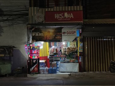 Ekim 2024, Endonezya, Surabaya 'da küçük bir market, geceleri renkli ışıklarla aydınlatılıyor. Çeşitli atıştırmalıklar, içecekler ve kızarmış tavuk satar..