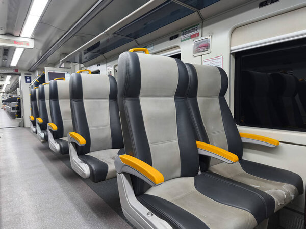 an empty train carriage with rows of seats and a clear view down the aisle.
