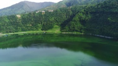 Telaga Menjer, Wonosobo 'nun nefes kesici hava manzarası. Etrafı yemyeşil ormanlarla, çay tarlalarıyla çevrili sakin bir göl ve yuvarlanan tepelerin arasına yerleşmiş dağınık konaklama yerleri sergiliyor..